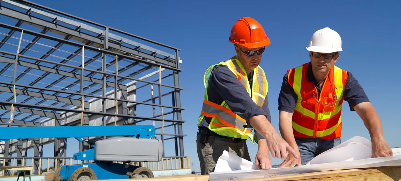 2 workers checking drawings by metal framework